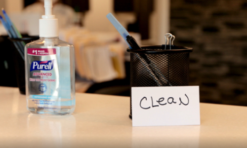 A hand sanitizer and pen stand on the clinic surface.